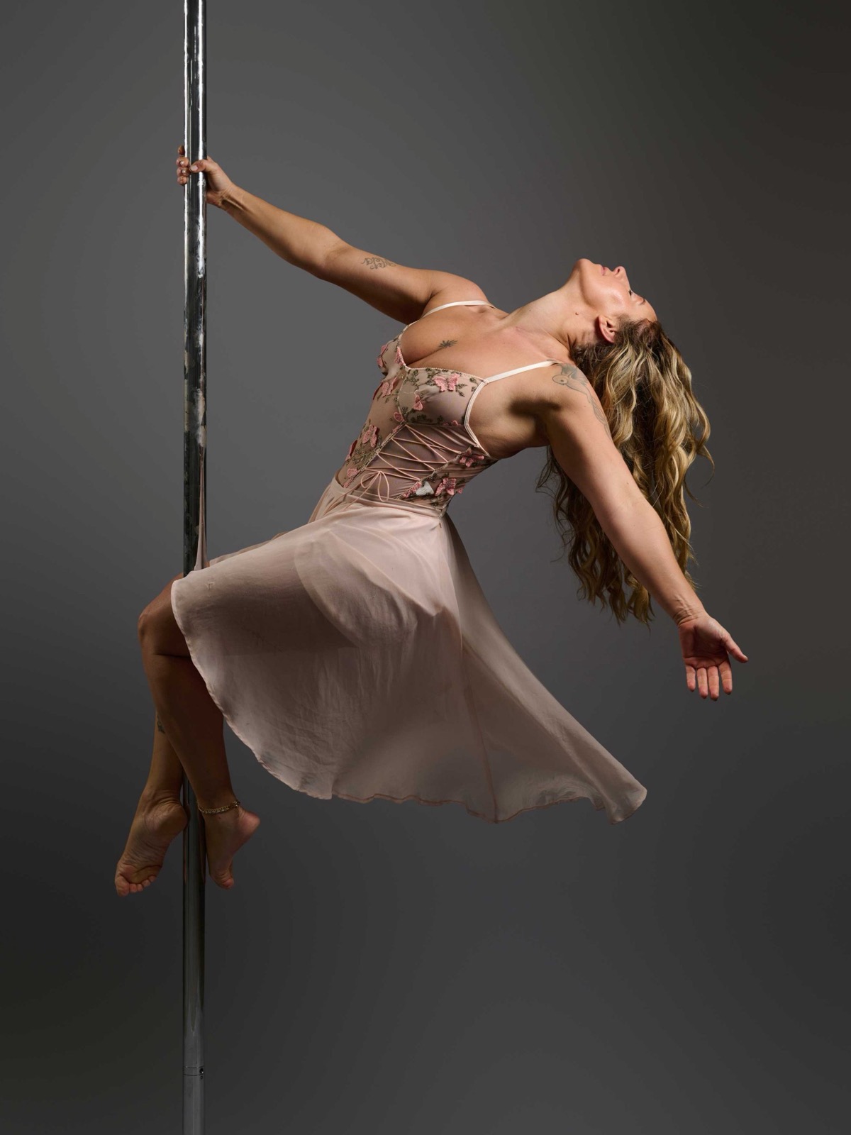 A student in a flowing skirt leaning back from the pole